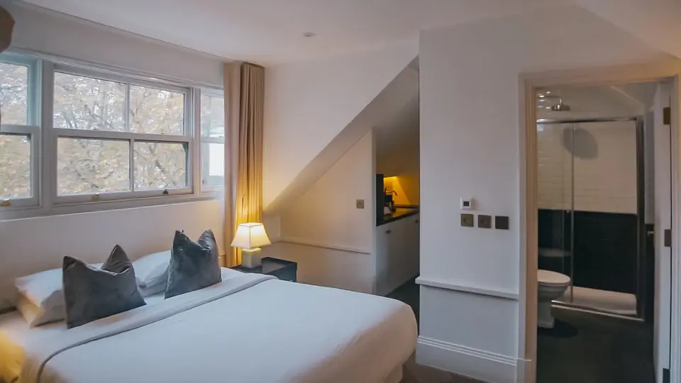 A guest bedroom under a sloped ceiling, with its own bathroom