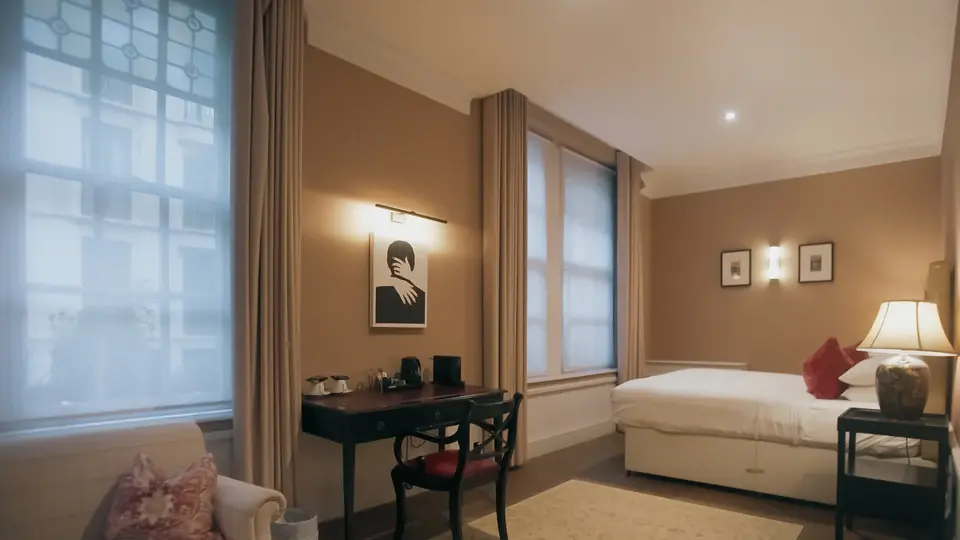 A guest bedroom with a leaded window, a desk and an armchair